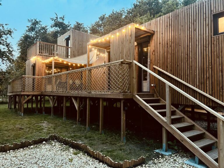 Façade en bois et terrasse sur pilotis en fin de journée